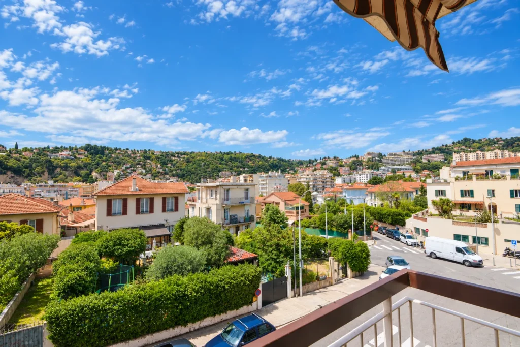 Vue depuis un balcon sur les maisons et collines de Nice Nord