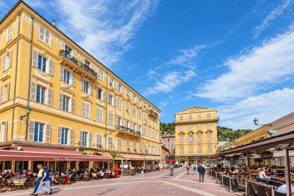 Place piétonne bordée de façades ocre et de terrasses dans le Vieux-Nice